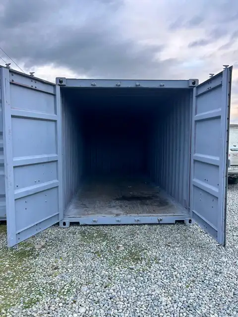 Contenedor de 20 pies con las puertas abiertas, se ve el interior vacío y el piso